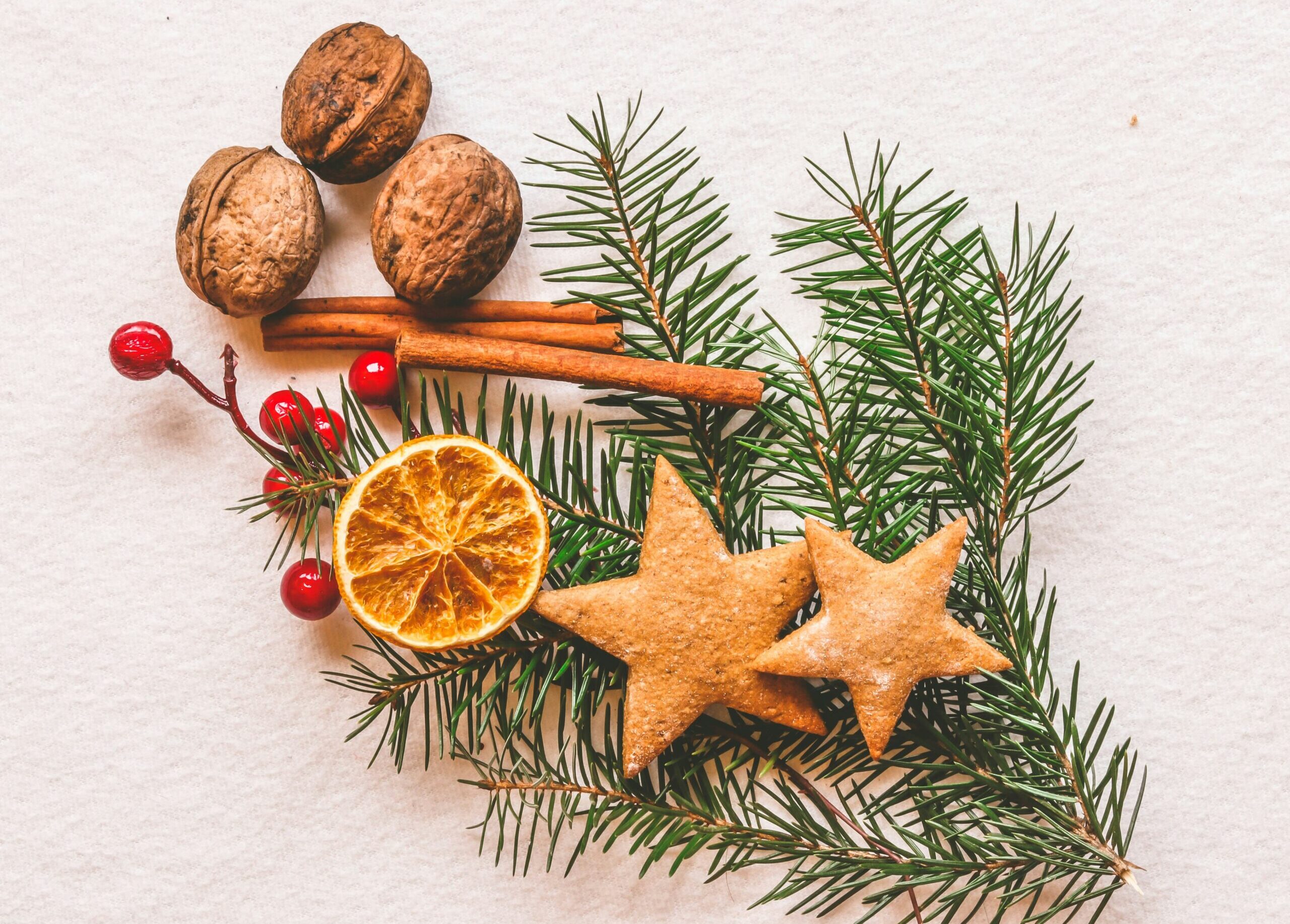 A budget-friendly Christmas decoration featuring a Christmas tree adorned with sustainable gingerbread cookies, nuts, and oranges against a white background.