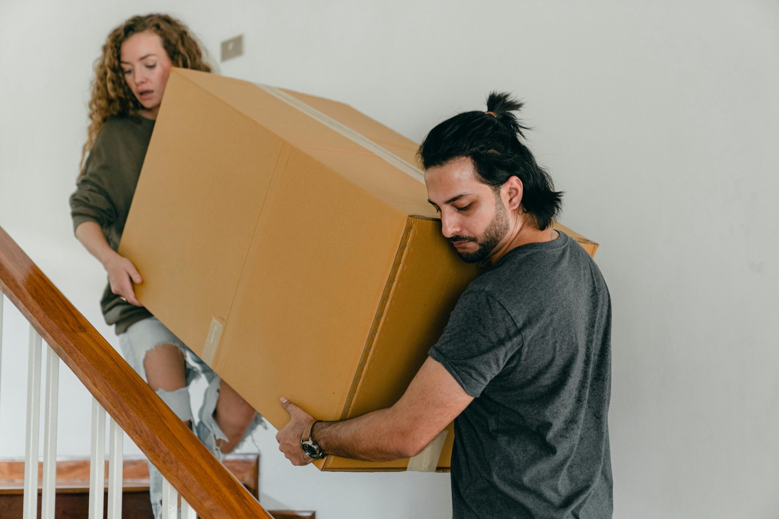 two people carrying a box down stairs