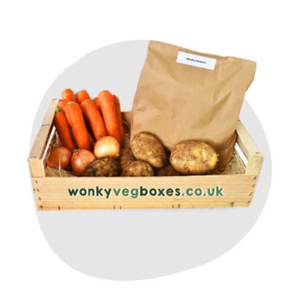 A wooden box labeled "wonky vegboxes.co.uk" contains carrots, potatoes, onions, and a brown paper bag.