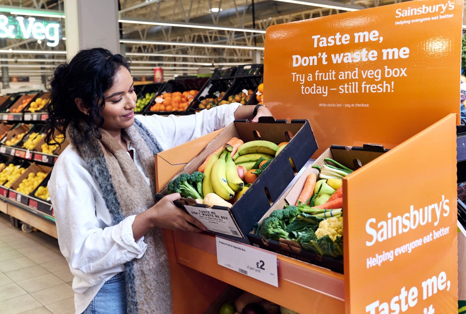 A person picks up a discounted fruit and vegetable box from a display in sainsburys supermarket. 