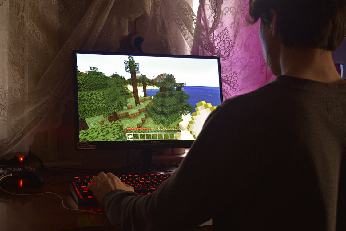 An image of a dimly-lit person playing the Minecraft video game