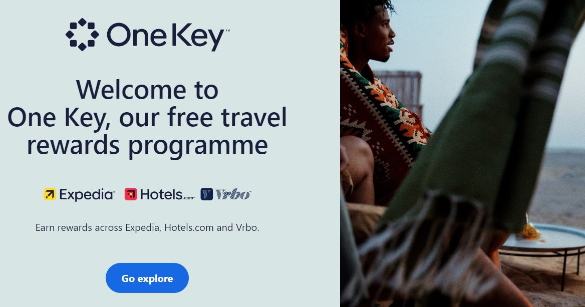 An ad for One Key's travel rewards program featuring images of Expedia, Hotels.com, Vrbo logos, and a person holding a striped blanket near a scenic outdoor setting.