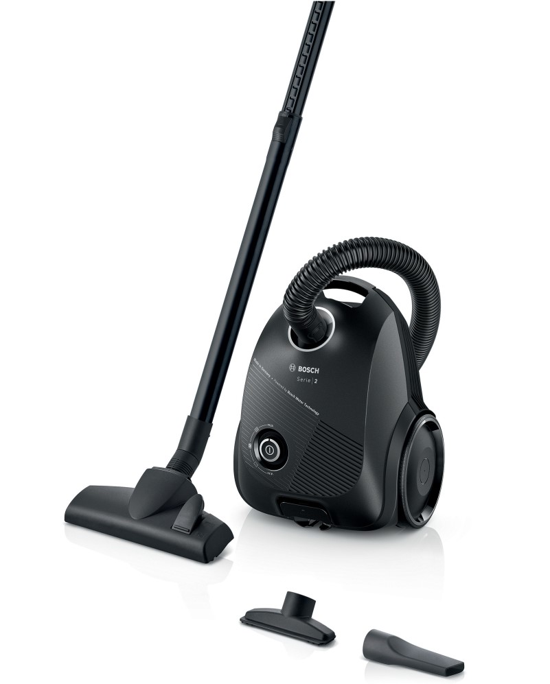 Black canister vacuum cleaner with a hose, main nozzle attached, and two additional attachments on the floor.