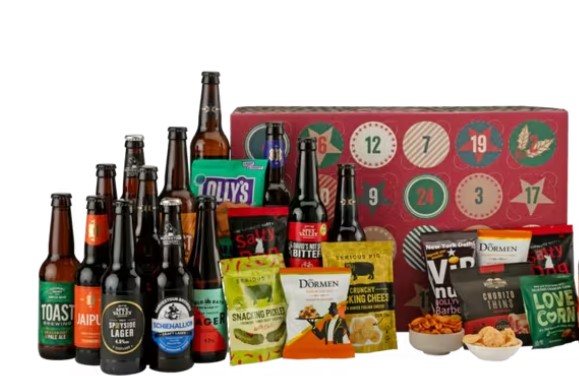 A selection of various bottled beers and snack packs is displayed in front of a red and green advent calendar box.