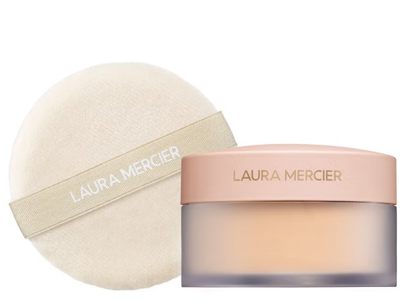 A beige powder container labeled "Laura Mercier" is placed next to a round, fluffy applicator with the same brand name.