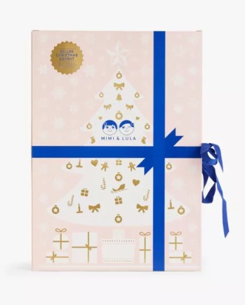 A pink box with a Christmas tree design, blue ribbon, and gold decorations. "Mimi & Lula" is printed on it.