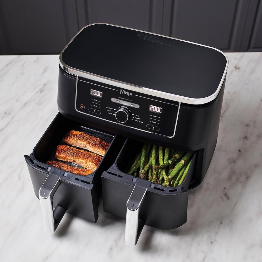 A dual-zone air fryer with salmon in one compartment and vegetables in the other