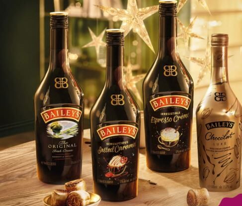 Four Baileys liquor bottles—Original Irish Cream, Salted Caramel, Espresso Crème, and Chocolat Luxe—grace a table adorned with star decorations. Tempted to try them all? Keep an eye out for the latest Baileys offers to find the best deals.