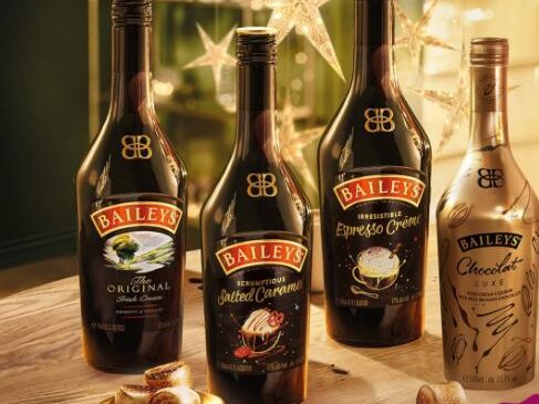 Four Baileys liquor bottles—Original Irish Cream, Salted Caramel, Espresso Crème, and Chocolat Luxe—grace a table adorned with star decorations. Tempted to try them all? Keep an eye out for the latest Baileys offers to find the best deals.