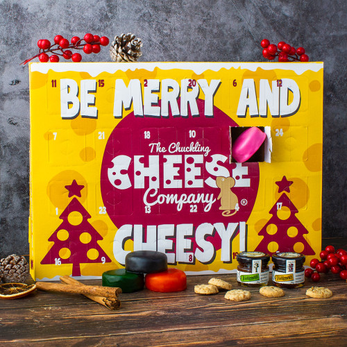 Advent calendar with "Be Merry and Cheesy!" sign, surrounded by small cheese rounds, crackers, and festive decorations.