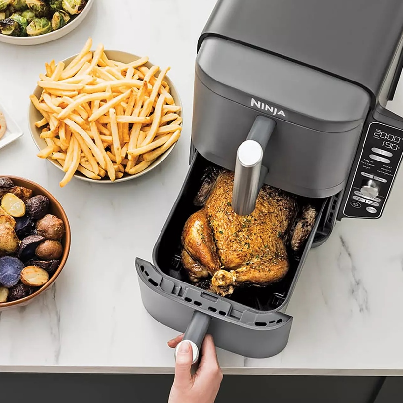 A Ninja double-stack air fryer with roast chicken inside, with other food like fries