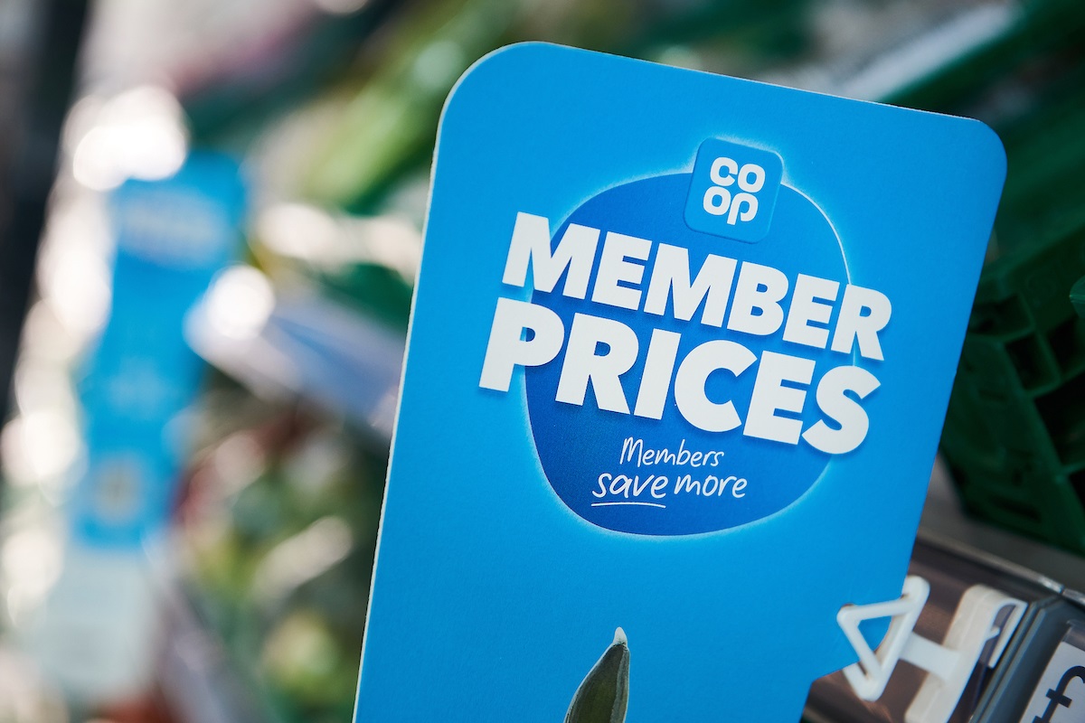 Close-up of a blue sign reading "Member Prices, Members save more" in a grocery store.