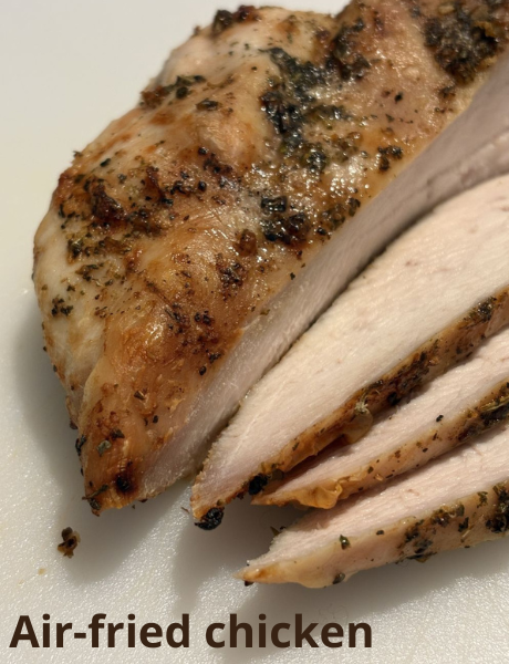 Sliced air-fried chicken breast with a golden brown crust on a white surface.