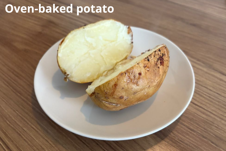 A halved oven-baked potato on a white plate, placed on a wooden table.