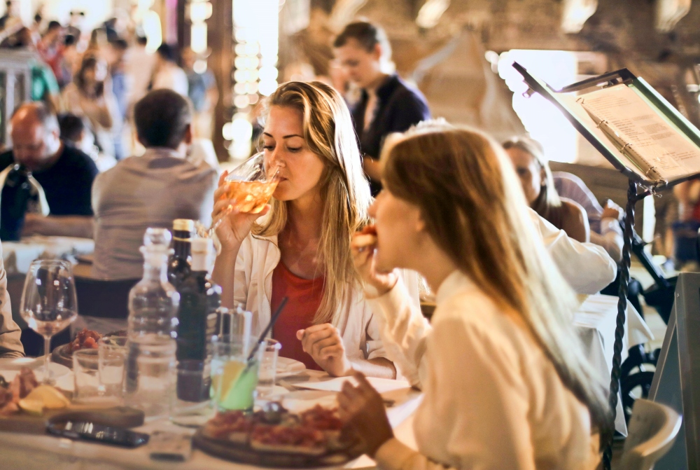 An image showing two women eating and drinking in a cafe