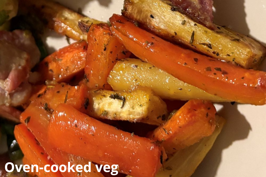 Close-up of oven-cooked carrots and parsnips seasoned with herbs on a plate.